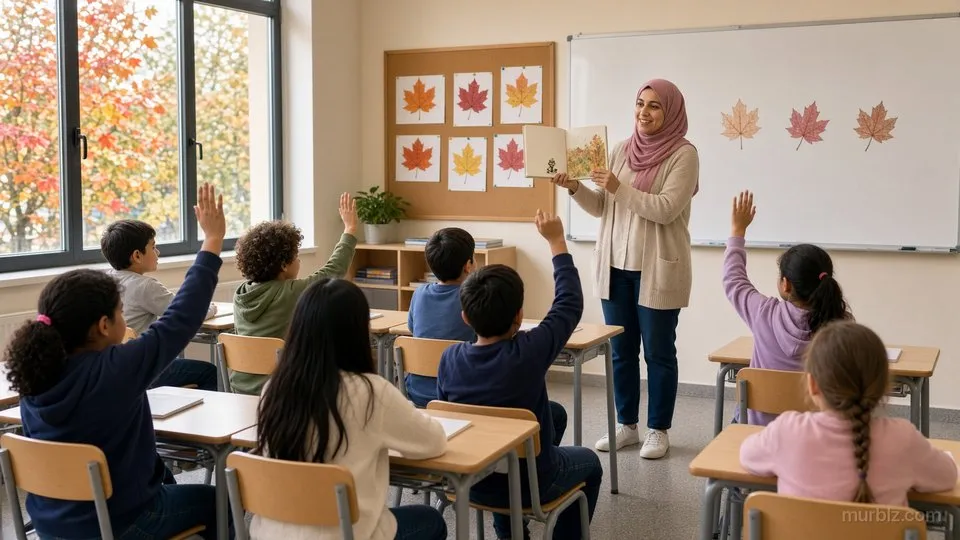 أمل بحجابها الوردي تعرض كتابًا مصوّرًا على تلاميذ الصف الثالث وأيديهم مرفوعة، وعلى اللوح أوراق قيقب ملوّنة، ومن النافذة أشجار الخريف