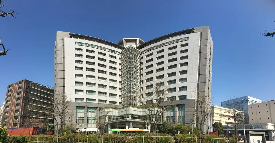 The Tokyo Regional Immigration Services Bureau, a large grey office building in Minato, under a blue sky